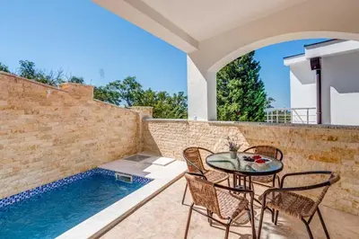 a patio with a table and chairs next to a swimming pool at Villa Hanna Apartments in Sutomore