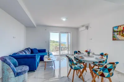 a living room with a blue couch and a table and chairs at Villa Hanna Apartments in Sutomore