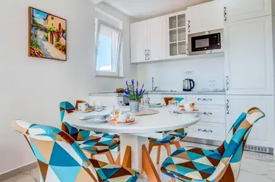 a white kitchen with a white table and chairs at Villa Hanna Apartments in Sutomore