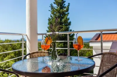 a table with two wine glasses on a balcony at Villa Hanna Apartments in Sutomore