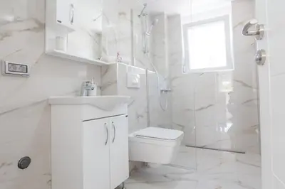a white bathroom with a toilet and a shower at Villa Hanna Apartments in Sutomore