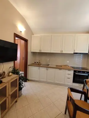a kitchen with white cabinets and a flat screen tv at Vidikovac in Kotor