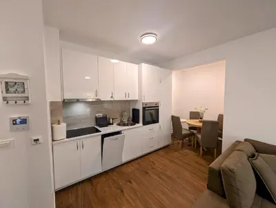 a kitchen with white cabinets and a table in a room at Dea apartment in Dobra Voda