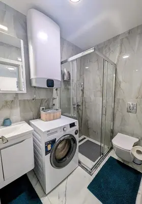 a bathroom with a washing machine and a shower at Dea apartment in Dobra Voda