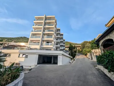 a tall building with a parking lot in front of it at Dea apartment in Dobra Voda