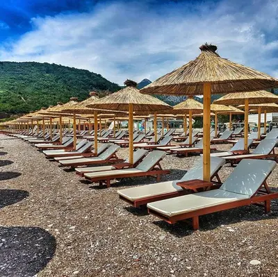 a row of lounge chairs and umbrellas on a beach at Villa MARINA CANJ 2 in Čanj