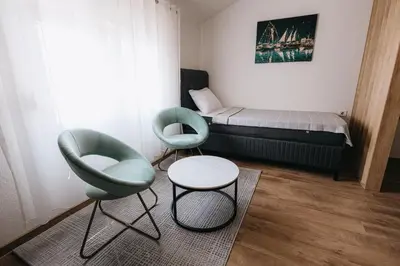 a room with a bed and two chairs and a table at Apartments Podgorička Vila in Podgorica