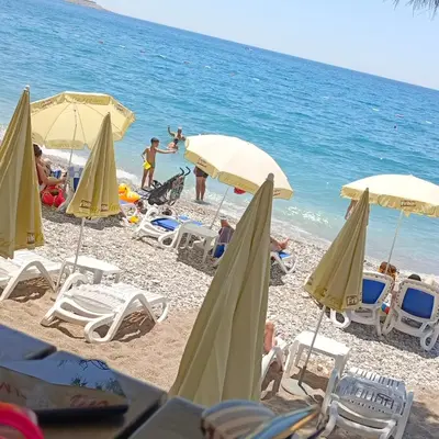 a beach with chairs and umbrellas and the ocean at Apartmani Kolovic Susanj in Bar