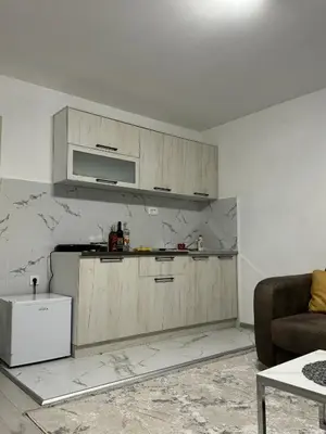 a kitchen with wooden cabinets in a living room at Apartment Airport DD in Mitrovići