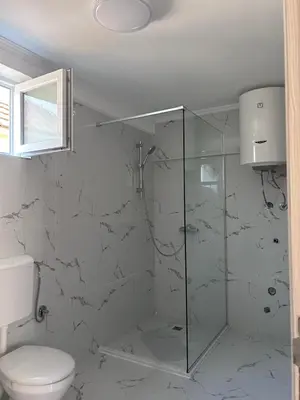 a bathroom with a toilet and a glass shower at Apartment Airport DD in Mitrovići