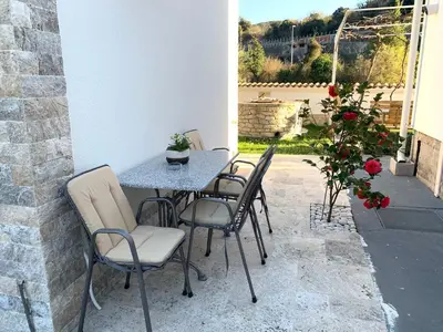 a table and chairs on a patio with roses at Markovic Village Apartments in Ulcinj
