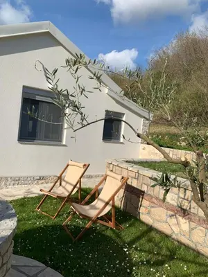 two chairs sitting in the grass in front of a house at Markovic Village Apartments in Ulcinj