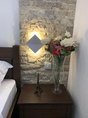 a vase of flowers on a table with a lamp at Markovic Village Apartments in Ulcinj