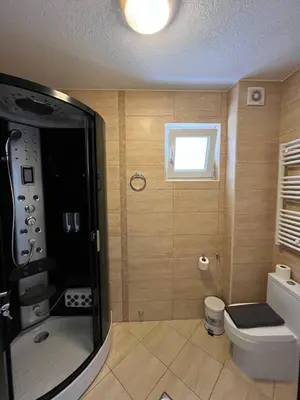 a bathroom with a shower and a toilet and a window at Fazenda 2 Becici in Becici