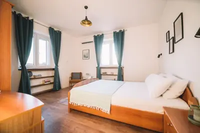 a bedroom with a bed and a desk and windows at Casa Hollaj in Vladimir