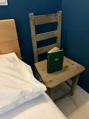 a book sitting on a wooden chair next to a bed at Lucky center Apartment in Podgorica
