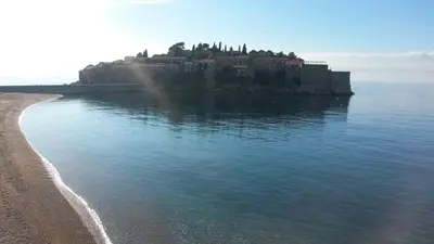 an island in the water next to a beach at Apartments Becici in Budva