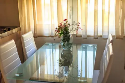 a vase with flowers sitting on a glass table at Villa Velzon Guesthouse in Budva