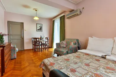 a bedroom with a bed and a chair and a table at Villa Velzon Guesthouse in Budva