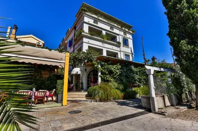 a white building with a table and chairs in front of it at Villa Velzon Guesthouse in Budva
