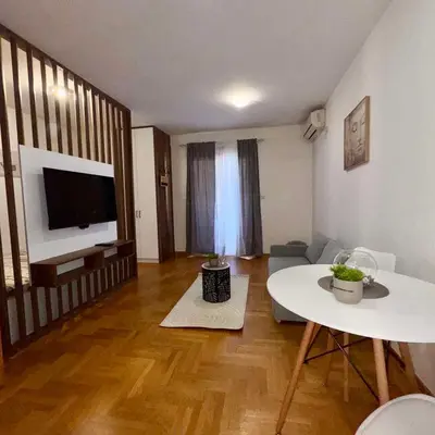 a living room with a white table and a television at Apartment Milana in Konik