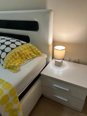 a bedroom with a bed and a lamp on a night stand at Apartment Enjoy City kvart in Podgorica