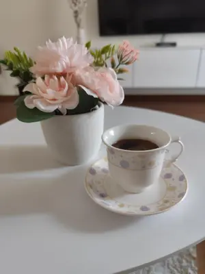 a cup of coffee and a vase of flowers on a table at Apartment Enjoy City kvart in Podgorica