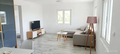 a white living room with a couch and a tv at Suite Madric in Pečurice