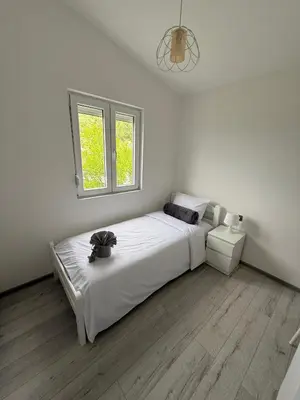 a white bedroom with a large bed and a window at Sisters residence in Kotor