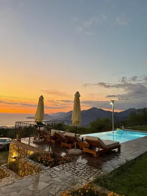 a pool with chairs and umbrellas at sunset at Old House Poda in Rap