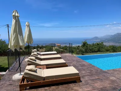 a group of lounge chairs and umbrellas next to a swimming pool at Old House Poda in Rap