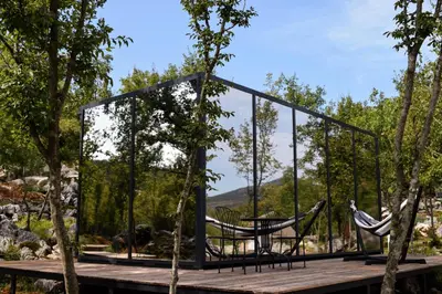 a glass house with a table and chairs on a deck at Oblun Eco Resort - Mirror Cabin in Podgorica