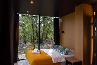 a bedroom with a bed and a large window at Oblun Eco Resort - Mirror Cabin in Podgorica