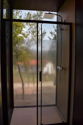 an open glass door with a view of a yard at Oblun Eco Resort - Mirror Cabin in Podgorica