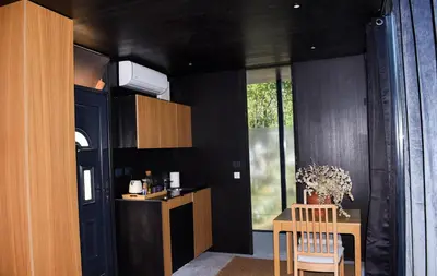 a kitchen with black walls and a table and chairs at Oblun Eco Resort - Mirror Cabin in Podgorica