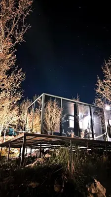 a glass house sitting on a bench at night at Oblun Eco Resort - Mirror Cabin in Podgorica