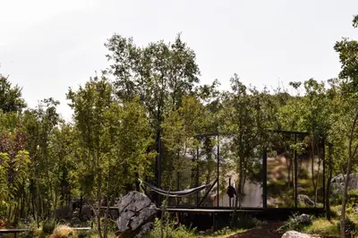 a glass house in a garden with a hammock at Oblun Eco Resort - Mirror Cabin in Podgorica