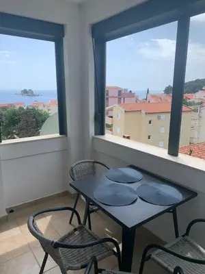a table and two chairs in a room with windows at Njaro del mar 16 in Petrovac na Moru