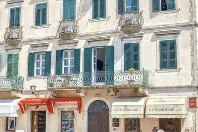 a large building with green shuttered windows and a store at Luxury Main Square apartment by MN Property in Kotor