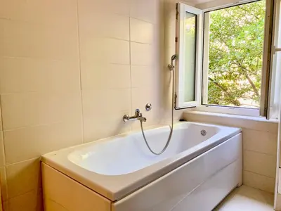 a bath tub in a bathroom with a window at Charming rooftop view in Kotor