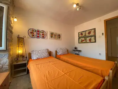 two beds in a bedroom with orange sheets at Charming rooftop view in Kotor