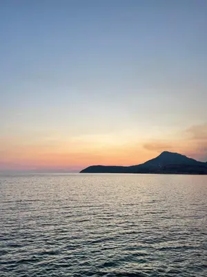a sunset over the water with a mountain in the background at Šušanj Bar in Bar, Susanj
