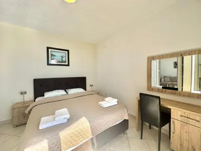 a bedroom with a bed and a desk and a mirror at Calma Vista Apartments by Vila Vanja in Budva