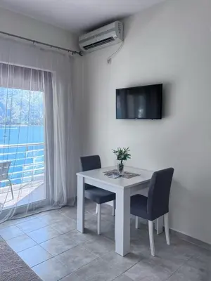 a white table with chairs and a television on a wall at Apartments Sofia in Kotor
