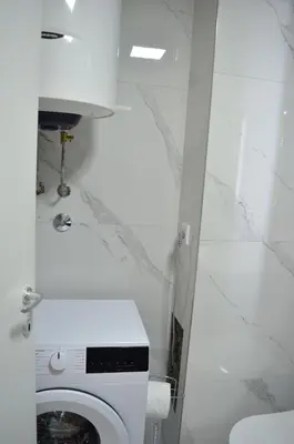 a white bathroom with a toilet and a sink at Apartman Kika in Sutomore