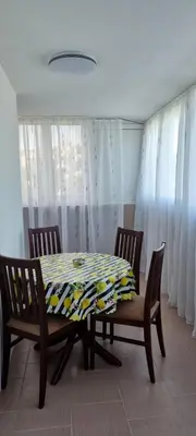 a dining room with a table and chairs and curtains at Apartman Kika in Sutomore