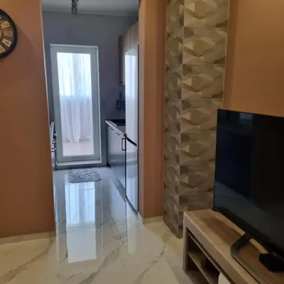 a living room with a television and a stone wall at Apartman Kika in Sutomore