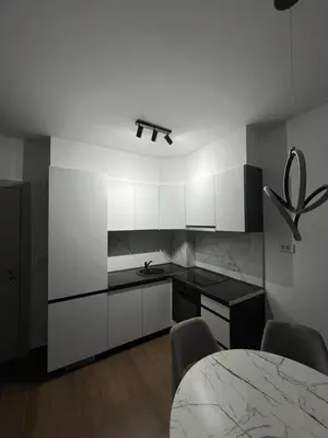 a kitchen with white cabinets and a table with chairs at Lucky in Babalonija