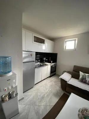 a small kitchen with white cabinets and a couch at Utjeha Montenegro in Masline