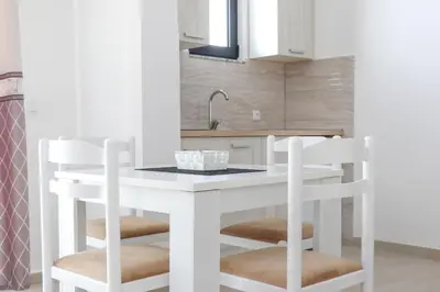a kitchen with a white island with two stools at You GO in Velika Plaža